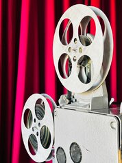 Gros plan sur un projecteur de cinéma vintage devant un rideau rouge vif, capturant l'ambiance des salles obscures classiques